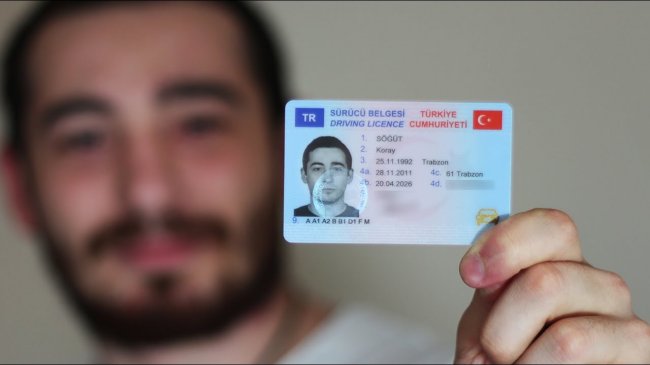 Yeni sürücü belgesini gösteren aday